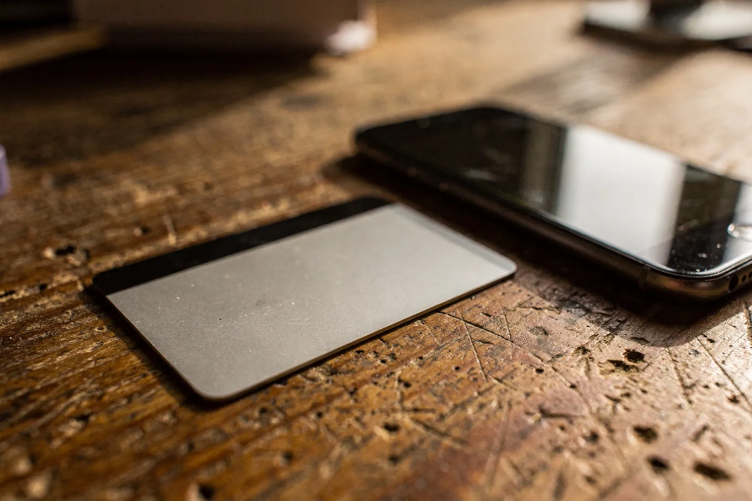 Bankkarte liegt neben einem Smartphone auf einem Holztisch