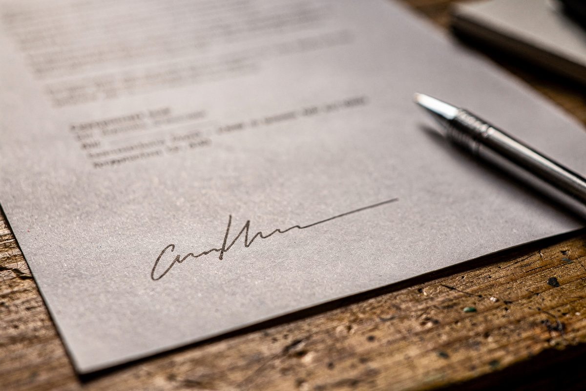 Nahaufnahme einer handschriftlichen Unterschrift auf einem Vertragsblatt