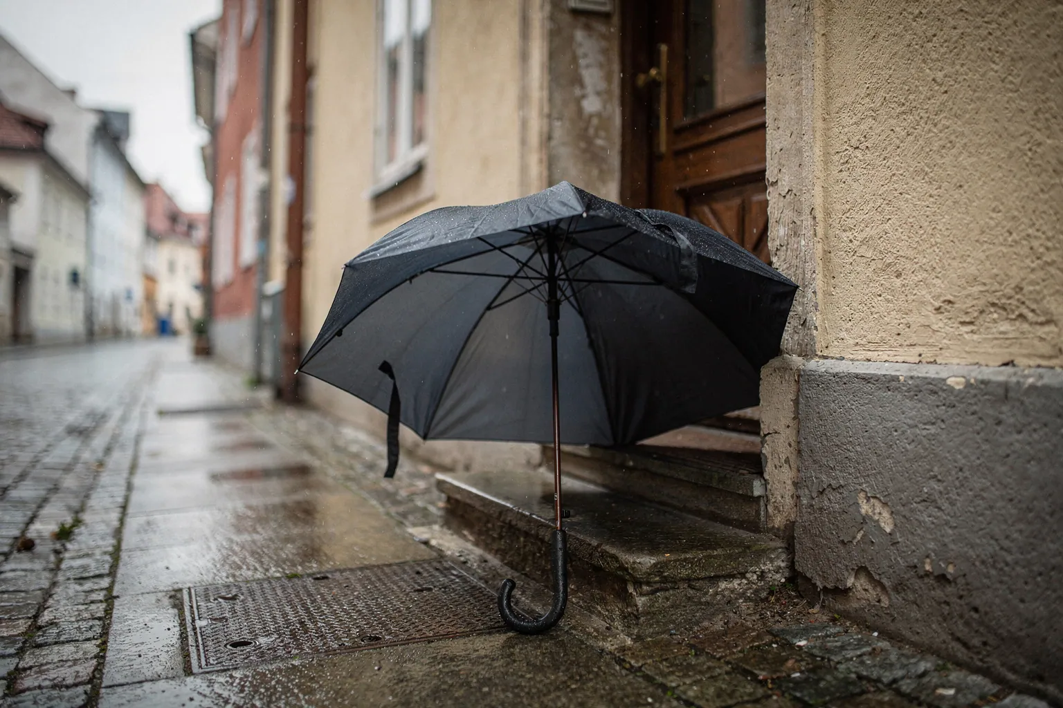 Ein aufgespannter Regenschirm lehnt an einer Haustür